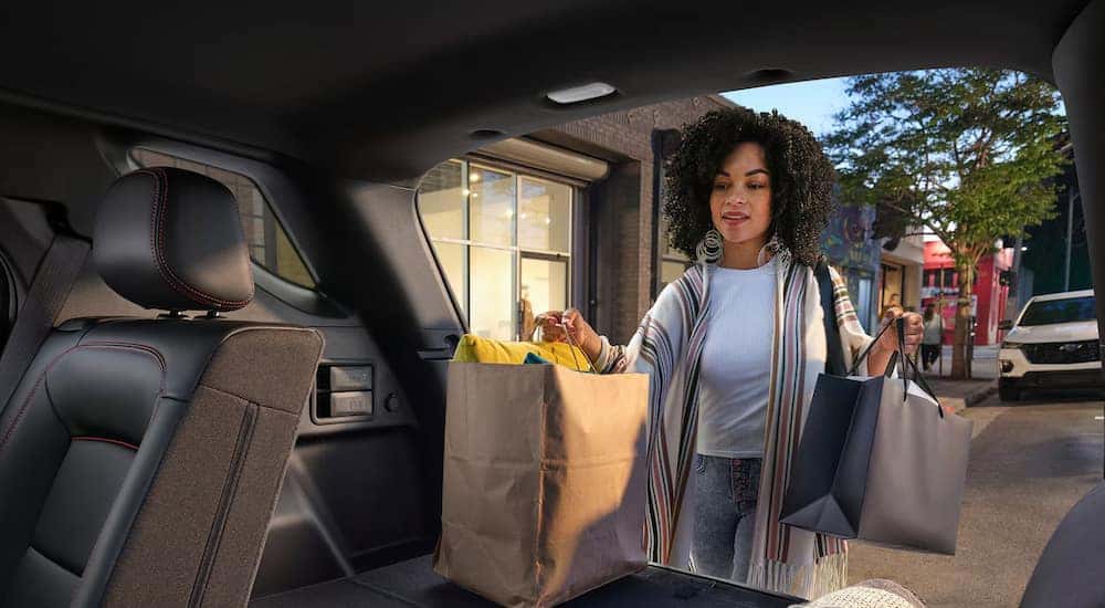 A woman loading groceries into the trunk of a 2024 Chevy Equinox RS.