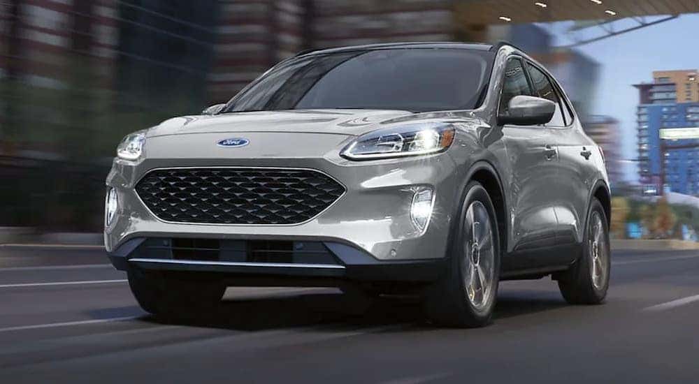 A silver 2021 Ford Escape driving from a dealer with used SUVs for sale near Delmar.