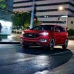 A red 2023 Ford Edge ST driving through a city at night.