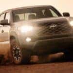A grey 2020 Toyota Tacoma driving off-road in a desert.
