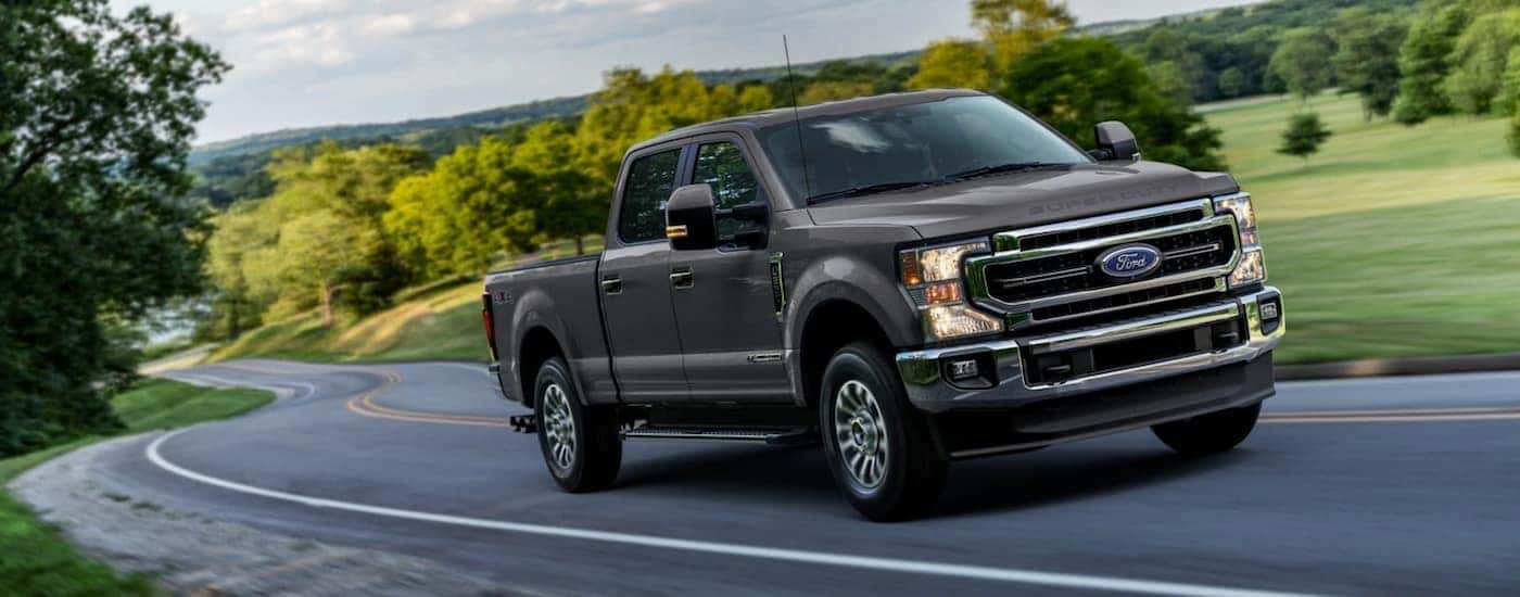 A grey 2021 Ford F-250 Super Duty driving from a dealer with used trucks for sale near Troy.