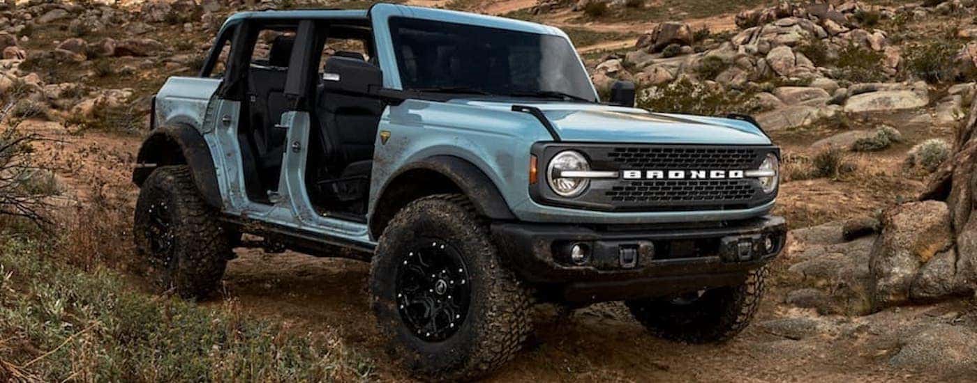 A popular used Ford Bronco for sale. a blue 2021 Ford Bronco, is shown driving off-road.