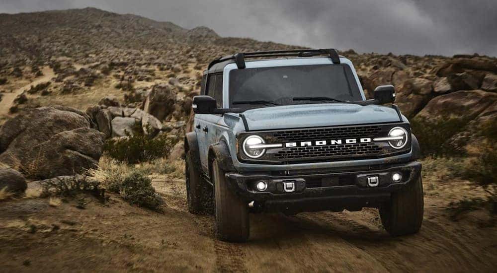 A light blue 2021 Ford Bronco driving off-road on a trail.