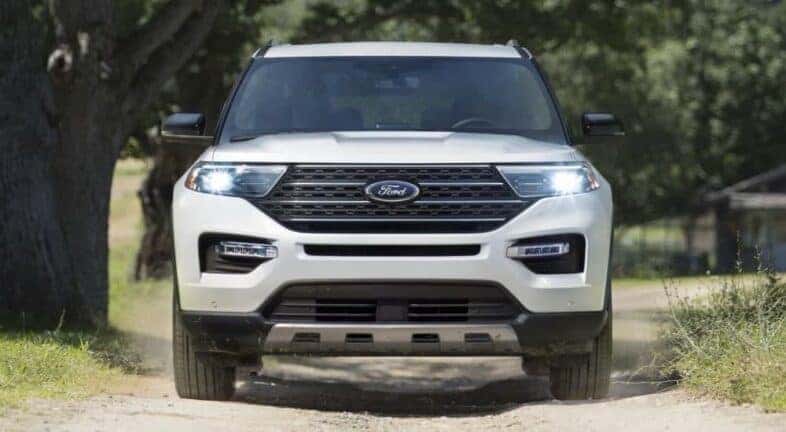 A white 2024 Ford Explorer King Ranch is shown driving on a dirt path.
