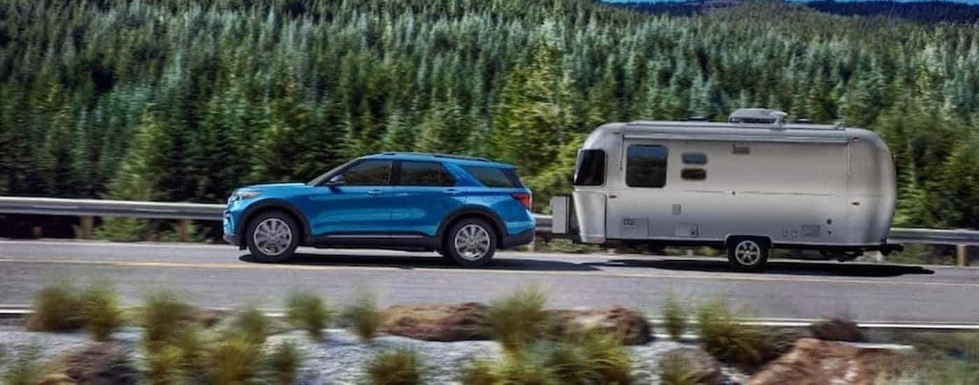 A blue 2023 Ford Explorer is shown towing a trailer.