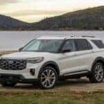 A white 2025 Ford Explorer Platinum is shown parked near a lake after viewing a Ford Explorer for sale.