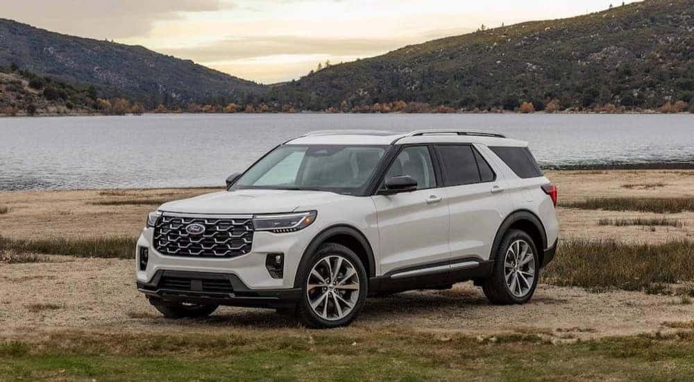 A white 2025 Ford Explorer Platinum is shown parked near a lake after viewing a Ford Explorer for sale.