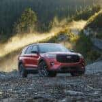 A red 2025 Ford Explorer parked off-road by a mountain.