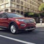 A red 2020 Ford Explorer driving from a dealer with a used Ford Explorer for sale.