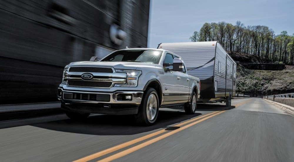 A silver 2018 Ford F-150 is shown towing a trailer.