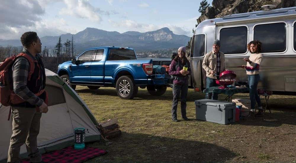 A blue 2022 Ford F-150 STX is shown parked on a campsite after viewing a used Ford F-150 for sale in Albany.