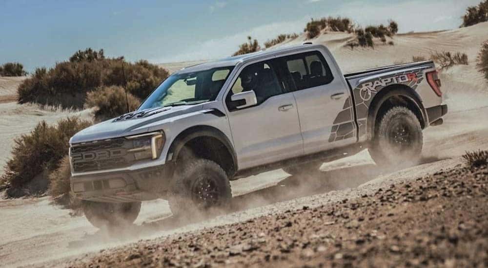 A white 2023 Ford F-150 Raptor R is shown off-roading.