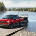 A red and black 2023 Ford F-150 Heritage Edition towing a boat out of a lake.