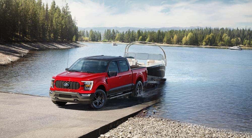 A red and black 2023 Ford F-150 Heritage Edition towing a boat out of a lake.
