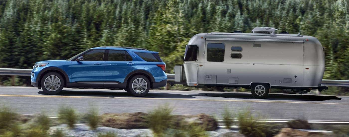 A blue 2021 Ford Explorer is shown towing a trailer.