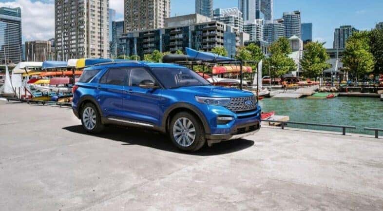 A blue 2023 Ford Explorer Limited is shown parked near many canoes.