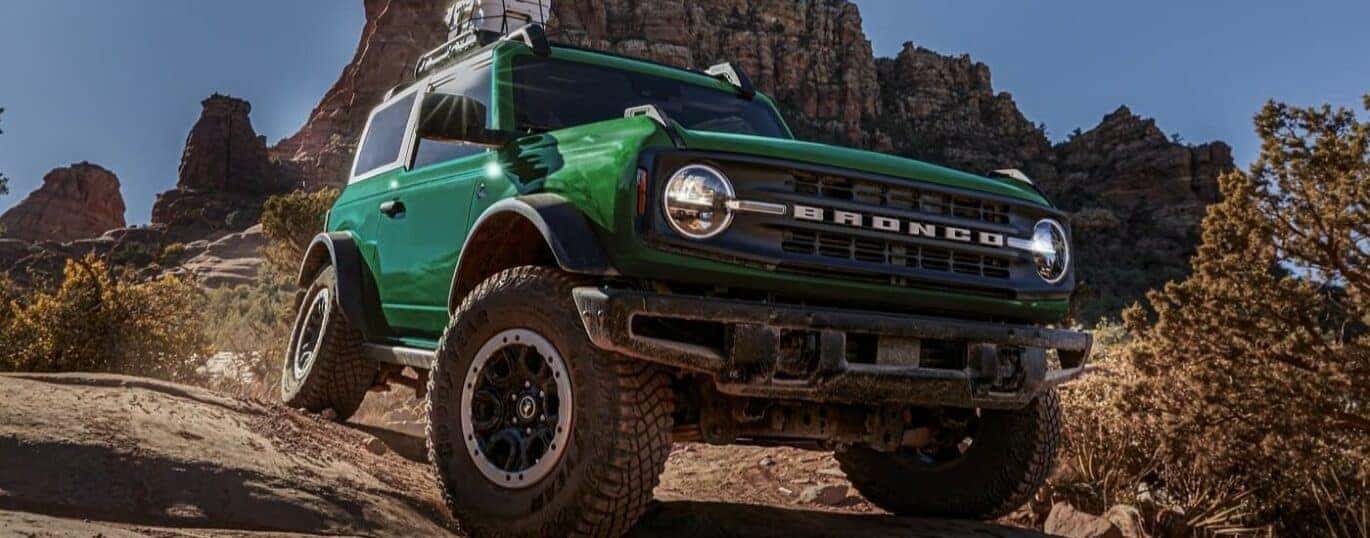 A green 2024 Ford Bronco Outer Banks driving down a hill.