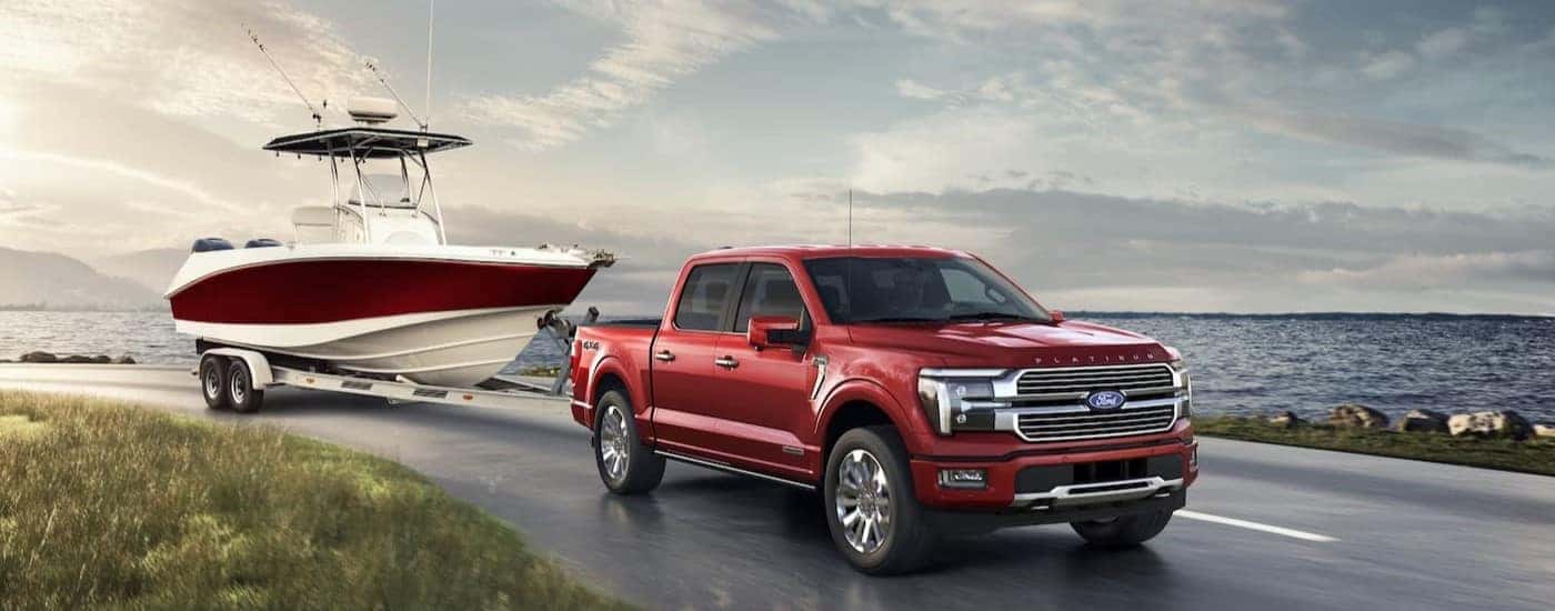 A red 2024 Ford F-150 Platinum is shown towing a boat.