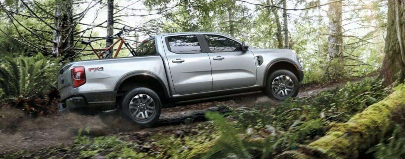 A silver 2024 Ford Ranger Lariat is shown driving off-road.