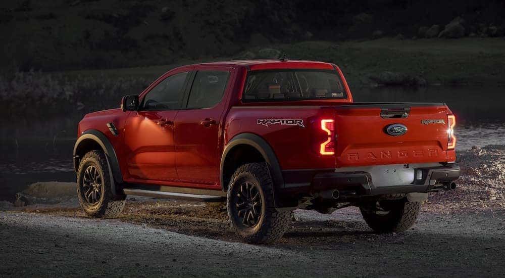 An orange 2024 Ford Ranger Raptor is shown from the rear at an angle.