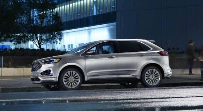 A silver 2023 Ford Edge is shown driving to view a used Ford for sale near Troy.