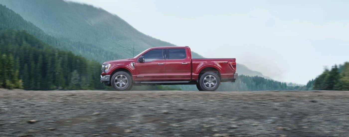A red 2023 Ford F-150 FX4 is shown driving off-road.