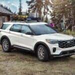 A white 2025 Ford Explorer parked outside a cabin and angled right.