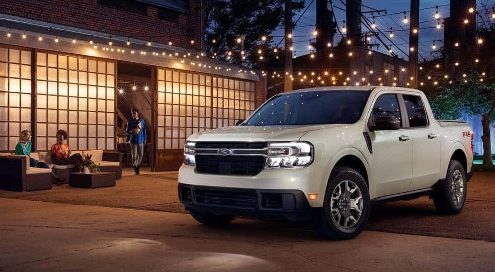 A white 2024 Ford Maverick LARIAT parked under cafe lights at night.