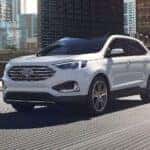 A white 2024 Ford Edge driving in a city.