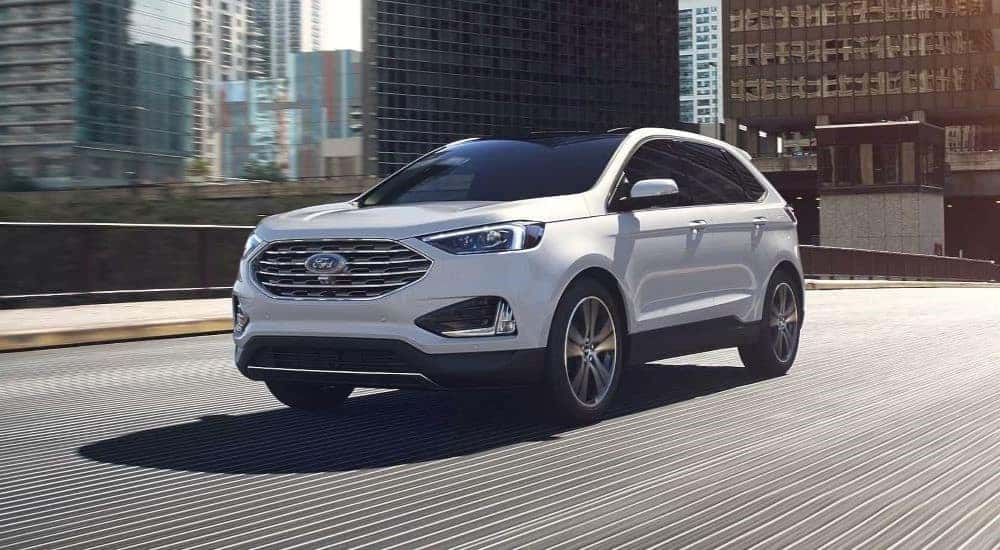 A white 2024 Ford Edge for sale driving in a city.