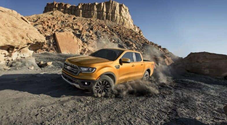 A gold 2022 Ford Ranger FX4 is off-roading and kicking up gravel.