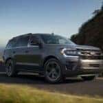 A gray 2024 Ford Expedition Platinum MAX is shown driving on a highway.