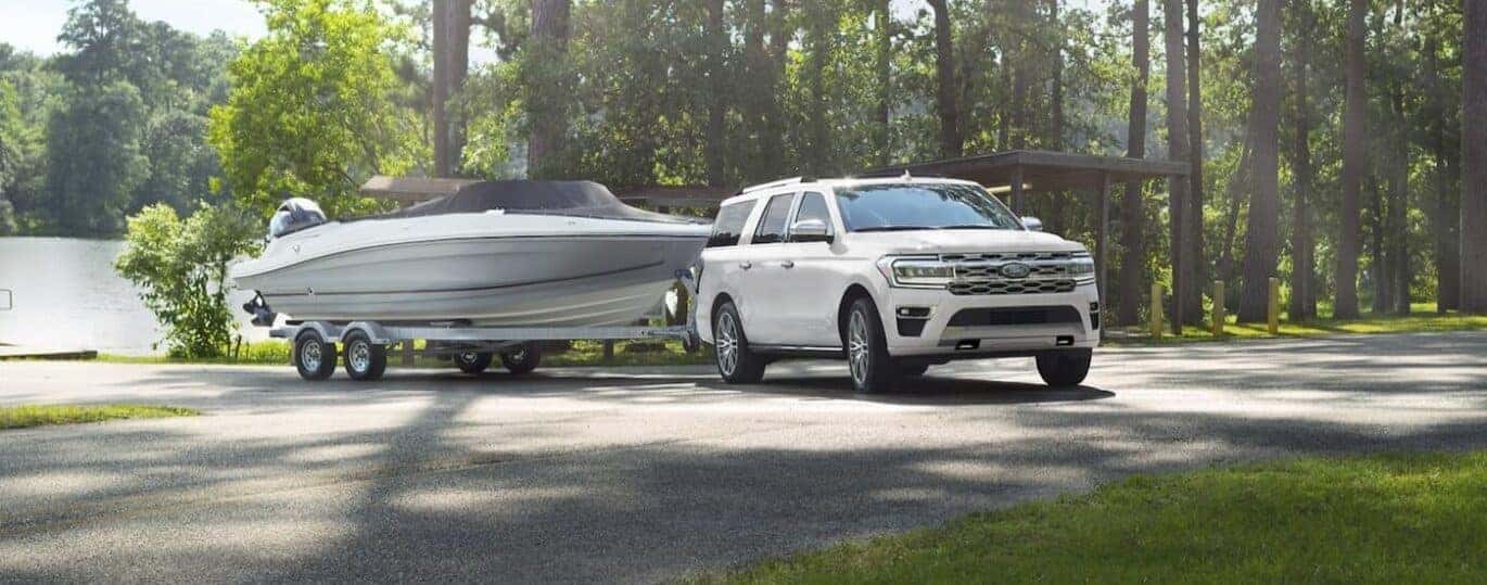 A white 2024 Ford Expedition is shown towing a boat.