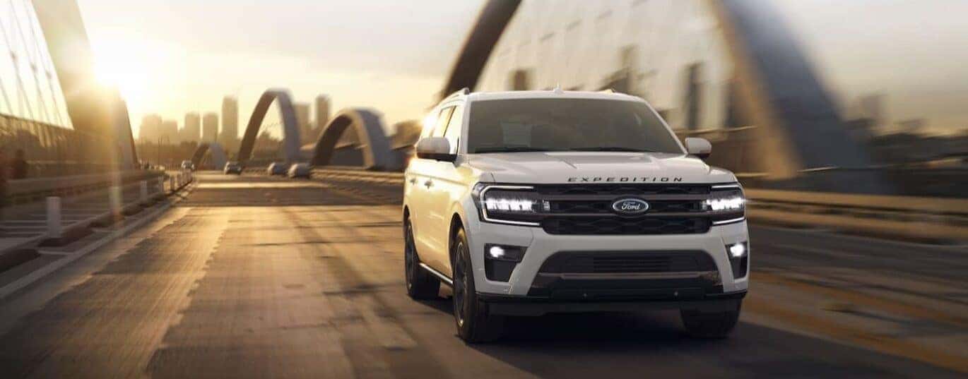 A white 2024 Ford Expedition is shown driving on a bridge.