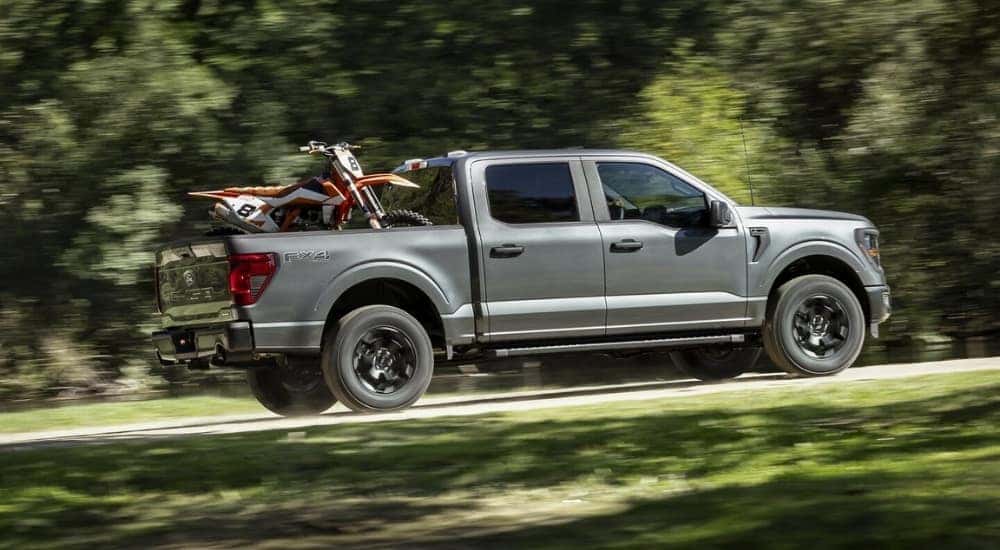 A grey 2025 Ford F-150 FX4 is shown driving on a trail.