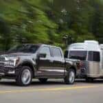 A grey 2025 Ford F-150 Platinum is shown towing an Airstream trailer.