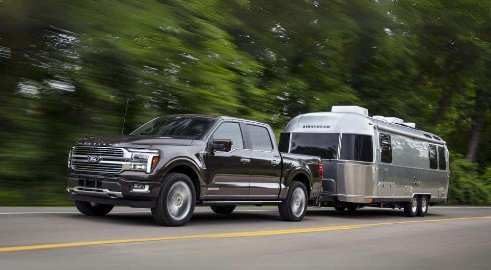 A grey 2025 Ford F-150 Platinum is shown towing an Airstream trailer.