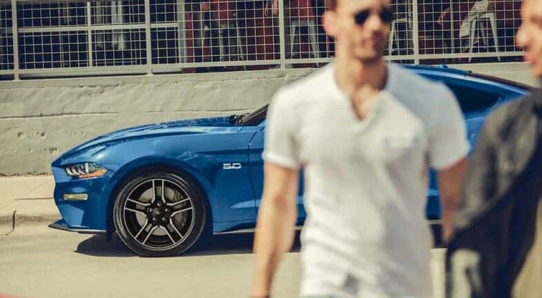 A man is shown walking away from a blue 2022 Ford Mustang GT.