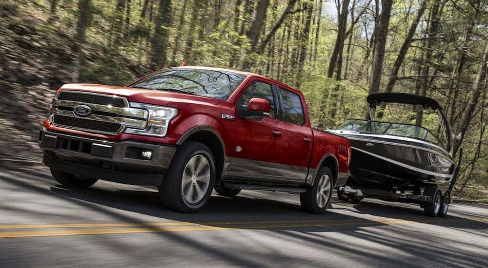 A red 2020 used Ford F-150 for sale near Delmar is shown towing a boat.
