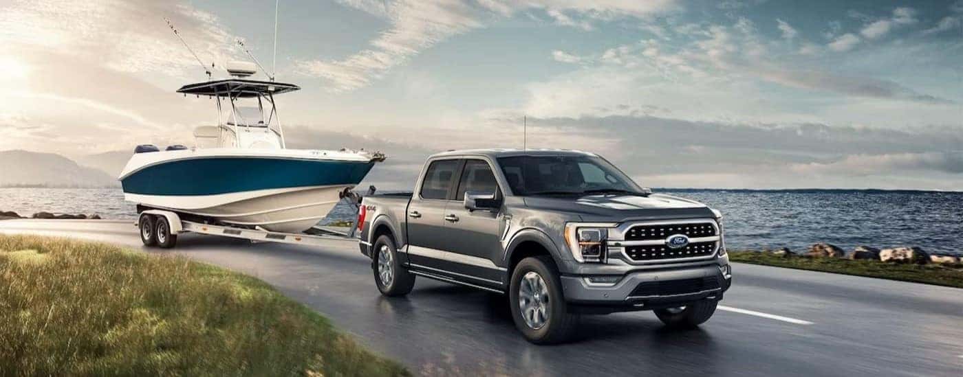 A silver 2023 Ford F-150 Lariat is shown towing a boat.