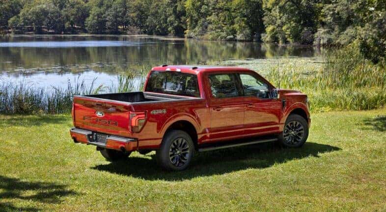 A red 2024 Ford F-150 Lariat is shown from the rear at an angle after leaving a dealer that has a Ford F-150 for Sale in Albany.