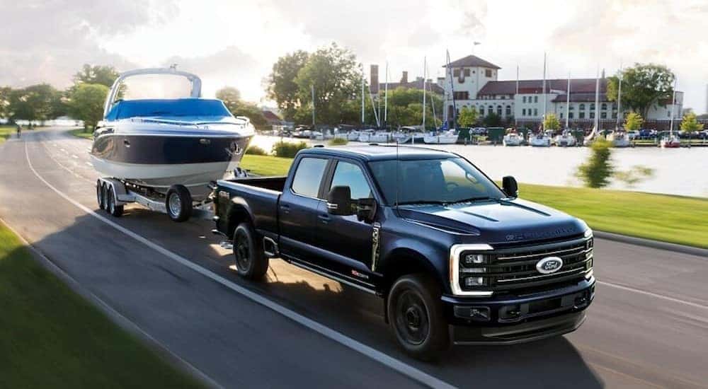 A black 2025 Ford F-350 is shown towing a boat