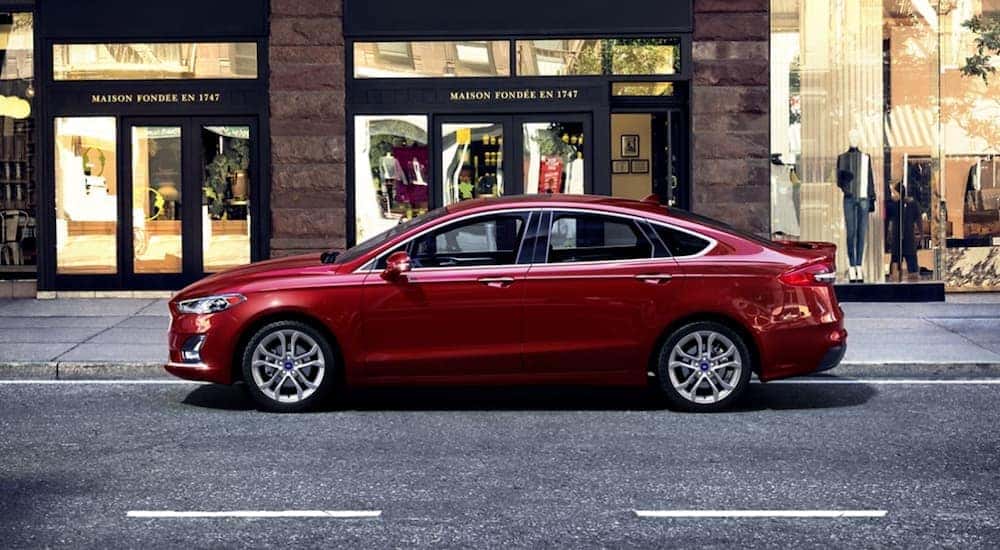 A red 2020 Ford Fusion is parked on the side of a city street after checking out a used Ford for sale in Colonie.
