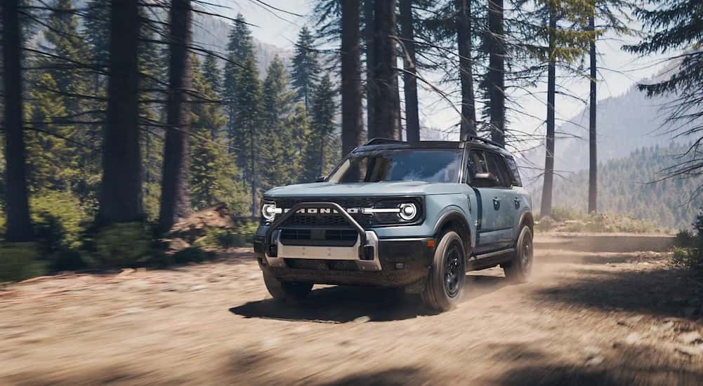 A light blue 2025 Ford Bronco Sport Outer Banks Sasquatch Package is shown driving in a forest.