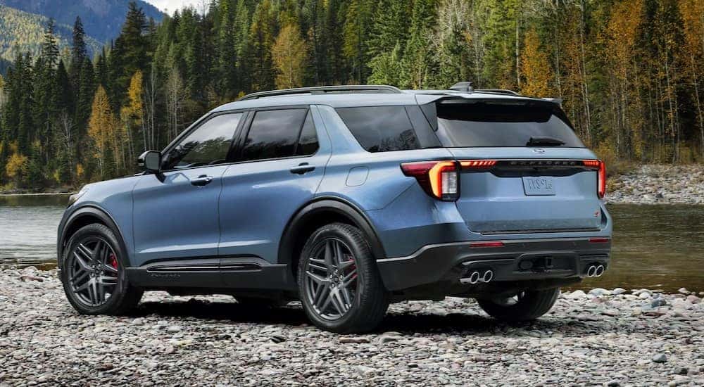 A blue 2025 Ford Explorer ST-Line is shown from a rear angle parked near a river.