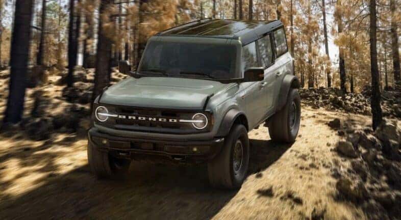 A blue 2021 Ford Bronco Wildtrak is shown driving off-road.