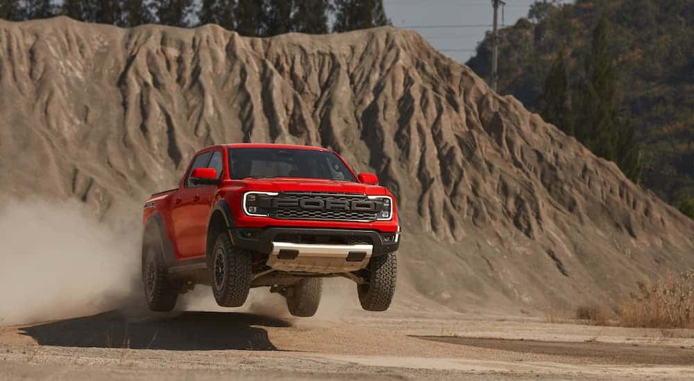 An orange 2025 Ford Range Raptor is shown from the front while jumping off-road.