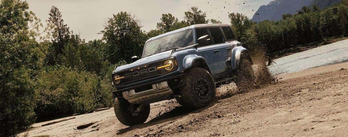 A blue 2024 Ford Bronco Badlands is shown off-roading after viewing a used Ford Bronco for sale in Albany.