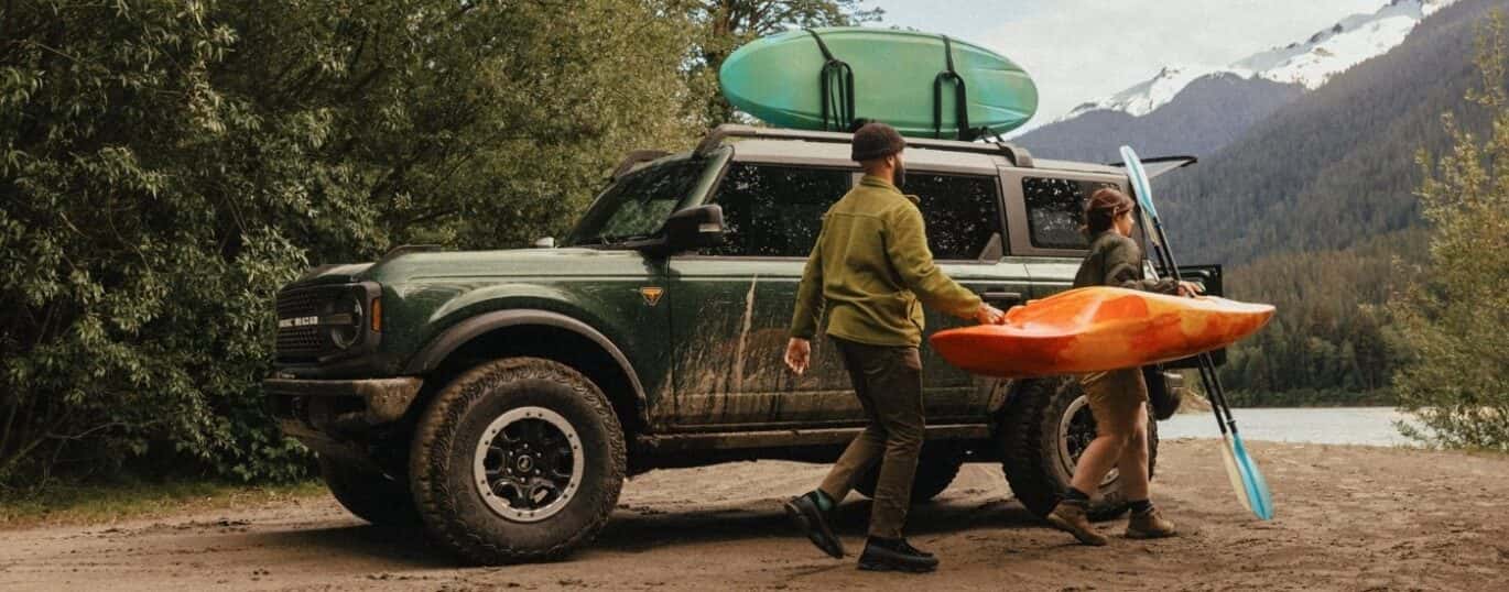 People are shown carrying a kayak near a gree 2025 Ford Bronco Badlands.