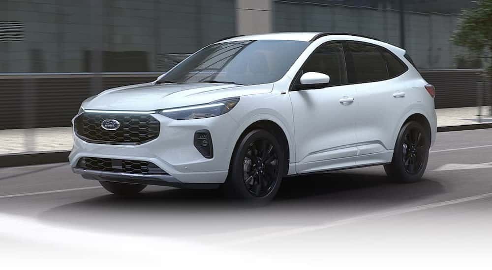 A white 2025 Ford Escape for sale in Albany is shown driving on a city street.